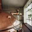 Alloa, Whins Road, Brewery, Brewhouse, lauter tun mezzanine floor area, interior
View showing Steeles Masher as it enters the Lauter Tun. This was added in 1986 when Castlemaine 4X lager began to be brewed on site under licence to Perkins of Brisbane, Australia. Grain stored in Grist Case 2 (which sits on roof of brewhouse) is fed by conveyor to the Steeles Masher. The grist is mixed here with water from Mash Tun no.2 into a thick consistency. More hot liquor is then pumped in from Mash Tun no. 2. The liquid sugar tanks are situated below this area