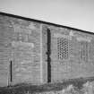 Detailed view from SE of blocked openings and windows on E side of Quinan stove or drying house, building R19, latterly converted to a narrow-gauge transit shed.