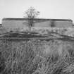 View from E of surviving Quinan stove or drying house, building R18, with concrete foundations of heater unit or apparatus house in foreground.  The 36 Quinan stoves were arranged symmetrically in pairs around a central heater unit.