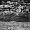 View of medieval graveslab set into wall of burial ground, NY 2577 8019.