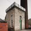 View from W of former beam engine house with cast iron roof tank made by G. Graham of Carlisle.  Also visible are the base of the boilerhouse chimney, and the NW end of the boilerhouse.