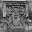 Courtyard, detail of carved panel in pediment above doorway in centre of south wall