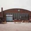 View from NNE end of hangar, showing brick gable with windows and door, and brick chimney stack