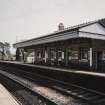 View from NW of S-bound platform, station offices and awning, with footbridge beyond