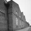 View from South West of South East frontage of works (onto Den Road), showing pilasters and segmentally-arched windows with moulded brick arches.  Note that the works was formerly a foundry, but later became a felt mill for Nairn's of Kirkcaldy