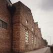 View from South West of South East frontage of works (onto Den Road), showing pilasters and segmentally-arched windows with moulded brick arches.  Note that the works was formerly a foundry, but later became a felt mill for Nairn's of Kirkcaldy