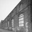 View from North East of South East frontage of works (onto Den Road), showing pilasters and segmentally-arched windows with moulded brick arches.  Note that the works was formerly a foundry, but later became a felt mill for Nairn's of Kirkcaldy