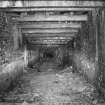 Cults Hill Limestone Quarry/Cults Lime Works.  View from N of the interior of the 20th century limestone mine, showing steel roof supports and brick wall lining.  Also visible is the double-track tramway remains with some of the metal and wooden sleepers still in situ.