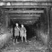 Cults Hill Limestone Quarry/Cults Lime Works.  View from N of interior of 20th century limestone mine with figures for scale.  Steel roof supports and brick wall lining with the remains of the tramway are also visible.