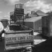 View from W of W end of lime works, showing road haulage vehicles in foreground, and dispatch hoppers in background