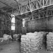 Interior view from SE of corner of lime store (a former aircraft hangar), showing corner uprights of latticed steel girders forming the internal frame of the building