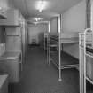 Interior view of 1935 Barrack Block showing ground floor dormitory with bunk beds and storage cupboards from S.