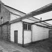 Aberdeen, Grandholm Works.
General view of West gable of dyehouse and wooden lean-to containing a pressure tank, view from South-West showing the top of the new boiler house chimney behind the dyehouse.