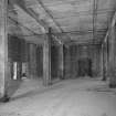 Broadford Mills: Interior view from SE within typical compartment of the warehouse, this one being at the NE end of the first floor level. The view shows the interior ferro-concrete frame of the bulding, and the brick exterior and interior dividing walls. Note that each of the compartments were designed to be isolated to prevent the spread of fire, and the hole in the dividing wall (left) had recently been made by contractors converting the building to dwellings. Note also that the concrete frame tapers as it rises through the building, the columns on the top floor being much thinner than those on the ground floor. Many of the finer facing bricks appear to have been made by the Seton Brick Works in Aberdeen