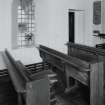 Interior. Vestry door, boarded walls, pews and window