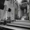 Interior. View of original part of church supported by beams from pews