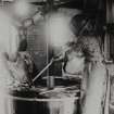 Photographic copy showing operator in protective suit tending a nitro-cotton nitrator.  The suit was designed to protect the operator from noxious fumes emitted from the acids in the nitrator RCAHMS, Permission to Reproduce: ICI Explosives