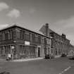 General view from SW of SW corner of works, showing elevations onto Norman Street (left) and French Street (right).  The view also shows the coloured enamel bricks decorating the office building occupying the SW corner of the works