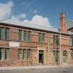 View from SSW of ornate brickwork comprising the elevation of the office building at the SW corner of works, which includes brown, blue and dark blue enamelled bricks within a fine facade of red facing brick with red sandstone insertions (including springers for arches above windows)