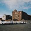 General view from SE of former cotton mill (right) and rear of stationery warehouse (left), also showing the stump of the boilerhouse chimney