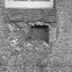 Reused socketed stone in external face of South wall of church, below window.