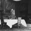 Interior. Reception room, showing an ornate relief ceiling, wooden panelled and pilastered walls and a small table with three chairs.