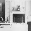 Interior. Long gallery. View of large, pale painted chimney piece with four engaged square Ionic columns, with an ornate clock on the mantelpiece.