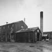 General view from WSW of, L to R, Evaporation Plant House, disused, and used previously to process Pot Ale waste from the stills, Still House/Boiler House Chimney, and Tun Room.