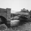 View from S of SE side of bridge, showing rubble-built outer arches, and central cast-iron span.