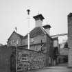 View from S of two Kilns (L), W end of Maltings, and overhead walkway between the two buildings. Note also the wind vanes on the two kiln ventilators.