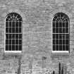 View of two large arched windows and blocked doorway and window in S wall of church.