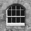 Detail of small arched window at ground level in S wall of church.