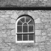 Detail of small arched window at roof level in S wall of church.