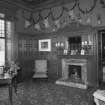 Interior. Ground floor view of sitting room from East looking towards the dining room showing the fireplace, original furnishings, fittings and stags heads