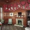 Interior. Ground floor view of sitting room from East looking towards the dining room showing the fireplace, original furnishings, fittings and stags heads