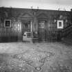 Interior. Ground floor view of entrance hall from East looking through to the sitting room and dining room beyond showing the panelled walls and pedimented doorcases