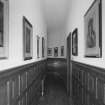 Interior. Ground floor view of framed engraving lined corridor in East wingcorridor