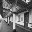 Detailed view from WSW along south-bound platform, showing ornate cast-iron columns and trusses supporting awning, and wooden facade of extended station buildings