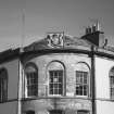 Detail of NW corner of upper storey showing three bayed quadrant and heraldic plaque.