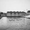 View across dam from SW of central buildings of distillery.