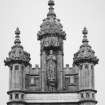 Detail of crocketed pinnacles and statue in niche of tower on N face.