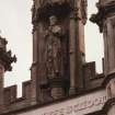 Detail of statue in niche of tower on N face .