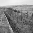 View from E of zig-zag perimeter fence to rear of torpedo stores.