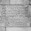 Detail of commemorative plaque to left of main entrance on W facade