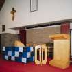 Interior. Detail of lecturn, font and communion table with cloth covering.