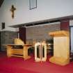 Interior. Detail of lecturn, font and communion table without cloth covering.
