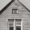 Top of gable, double window with carved panel containing monogram above, detail