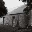 View from SW of front elevation showing harled rubble walls and corrugated iron roof.