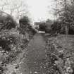 View of gravel path in front of plant border leading to garden front of Geanies house