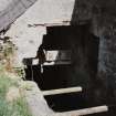 Detail showing water wheel house (water wheel removed) and remains of sluice and lade. The iron flat belt pulley at the top left side of the view is driven from a tractor and powers a grain bruiser